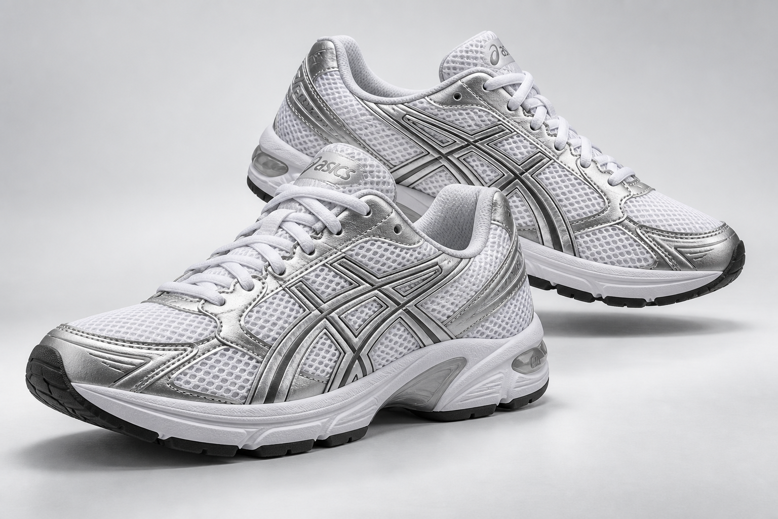 A pair of silver and white ASICS trainers in a sculptural studio arrangement